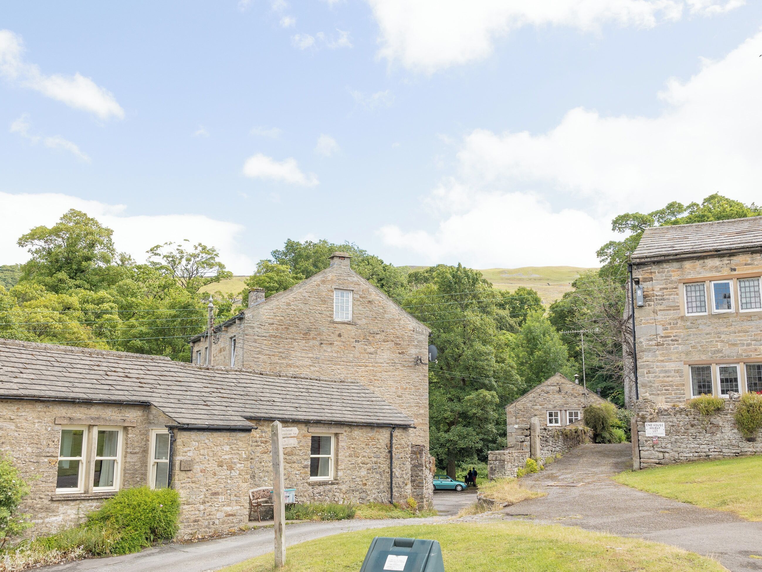 A stone building with a pitched roof, a small window, and a signpost in front.
