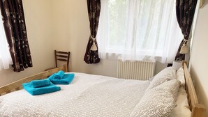 Un lit simple avec une couvre-lit à motifs, deux oreillers et deux serviettes pliées.