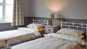 Une chambre avec deux lits, une table de chevet avec une lampe et une fenêtre avec des rideaux.