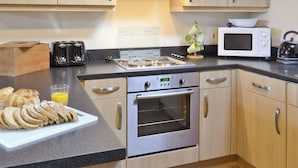 A modern kitchen with stainless steel appliances, wooden cabinets, and a granite countertop.
