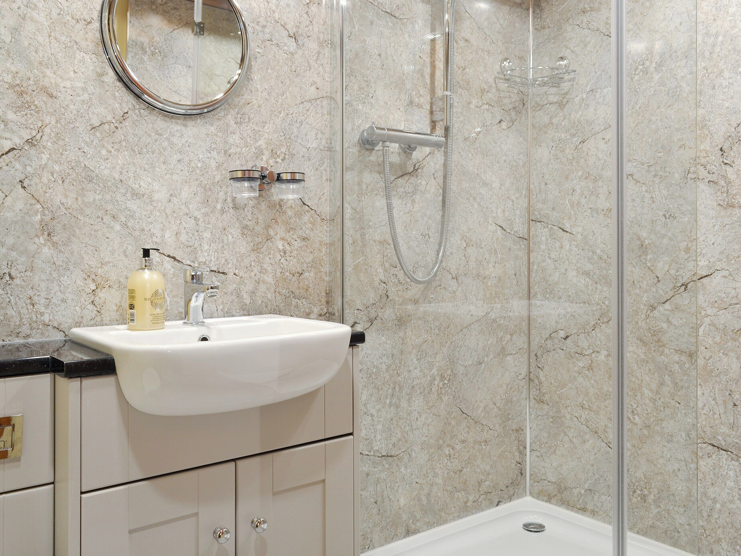 A bathroom with a white sink, a mirror, and a shower enclosure.