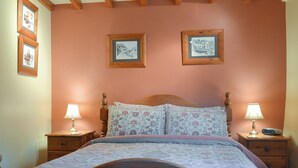 Una camera da letto con un letto in legno, biancheria da letto floreale, due comodini con lampade e due quadri appesi al muro.