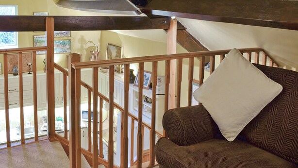 Una stanza accogliente con una scala in legno, un divano con motivo decorativo e vista su un angolo cottura.