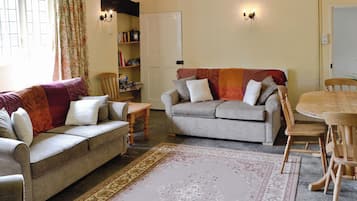 A cozy living room with two sofas, a wooden dining table, and a bookshelf.
