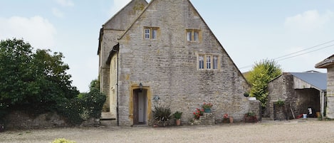 A stone building with a pitched roof, a door, and windows.