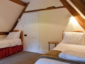 Une chambre avec deux lits simples, un plafond en bois, une porte blanche et une petite table en bois.