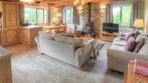 A cozy living room with a fireplace, wooden furniture, and large windows. - Hadrians Garden Villa (Henshaw, near Haltwhistle)