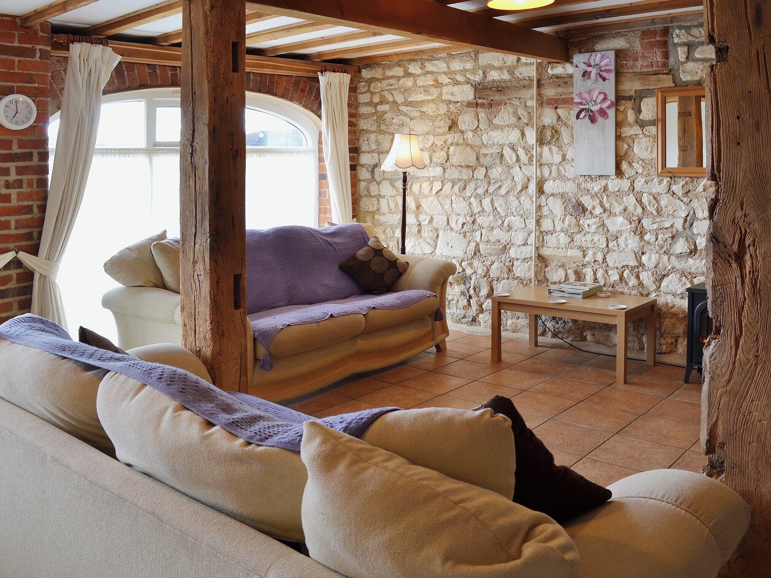 A cozy living room with a stone wall, a sofa, a table, and a lamp.