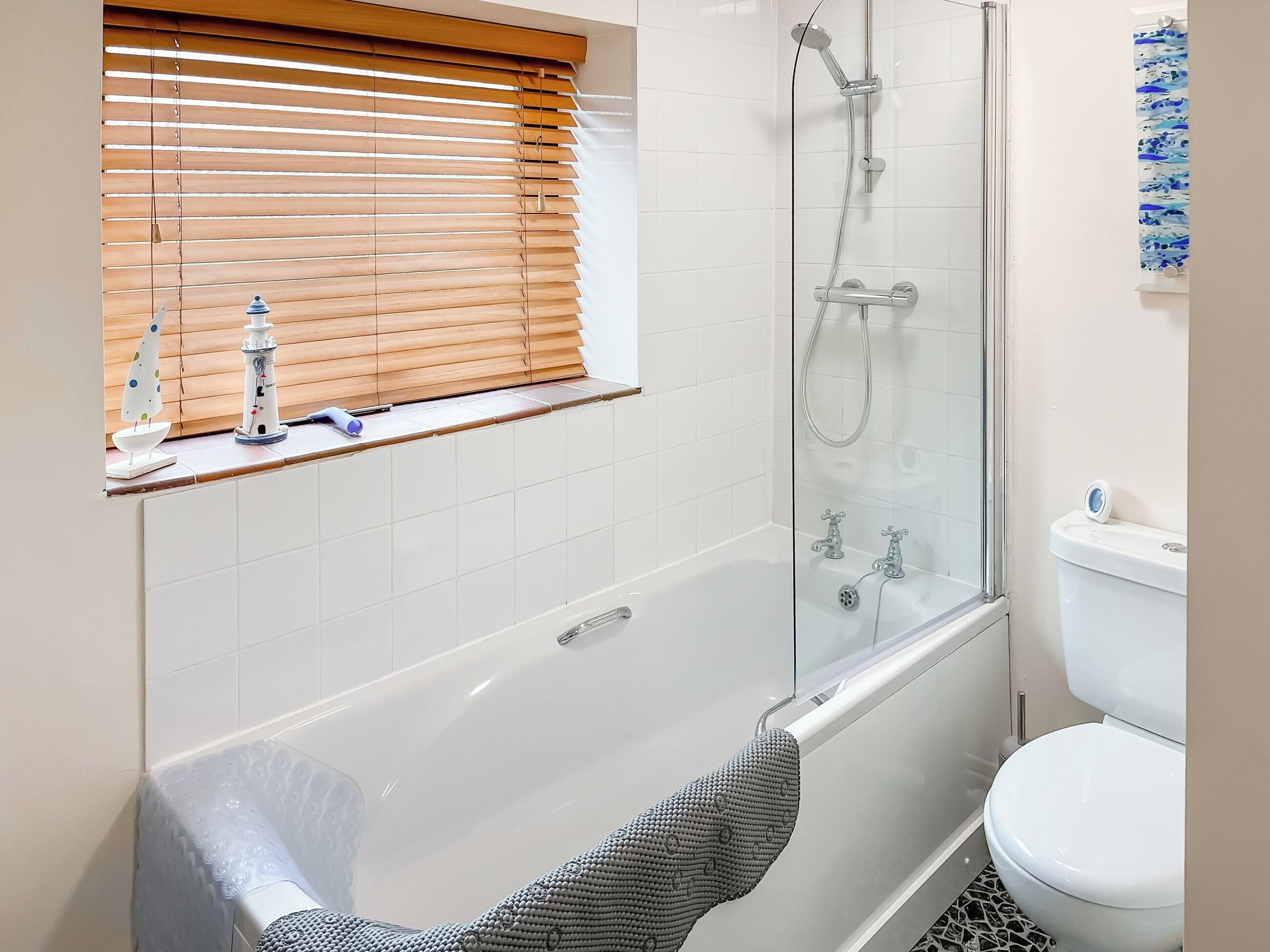 A modern bathroom with a glass-enclosed shower, a white bathtub, and a toilet.