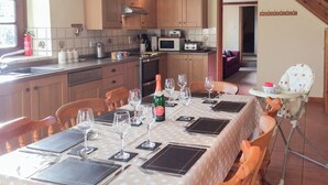 A dining area with a table set for a meal, a bottle of champagne, and a high chair.