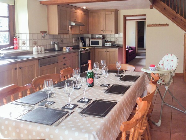 A dining area with a table set for a meal, a bottle of champagne, and a high chair.