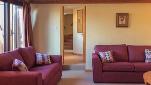 A living room with two red sofas, a wooden coffee table, and a staircase leading to another room.