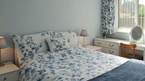 A bedroom with a bed, bedside tables, a desk, a chair, and a window with curtains. - 1 bedroom accommodation in Polstead (Polstead)