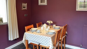 A dining area with a table set for four, featuring a polka dot tablecloth, white plates, and a vase of flowers. - 1 bedroom accommodation in Polstead (Polstead)