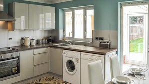 Une cuisine de taille réduite équipée d’un lave-linge, d’un grille-pain et d’un évier.