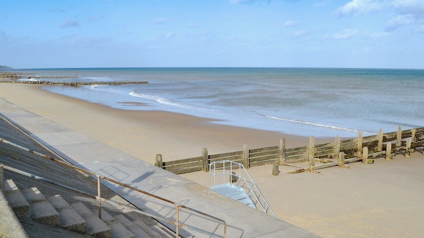 Une plage avec une promenade en bois et des marches descendant vers le rivage.