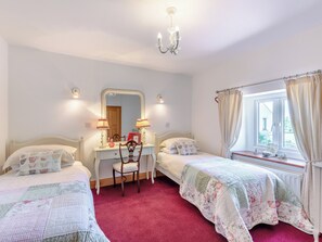 A bedroom with two single beds, a dresser, a chair, a mirror, and a window with curtains. - New Park Farm - Church Cottage (near Keswick)