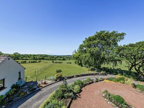 Ländliche Landschaft mit einem weißen Gebäude, einer gewundenen Straße und einem großen Baum.
