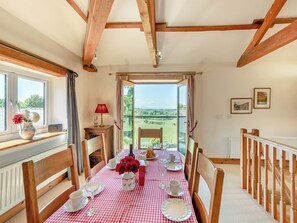 A dining area with a checkered tablecloth, wooden chairs, and a view through a glass door. - New Park Farm - Church Cottage (near Keswick)