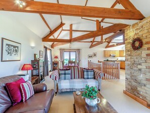 A cozy living room with a brown leather sofa, a plaid blanket, and a wooden coffee table with a plant. - New Park Farm - Church Cottage (near Keswick)
