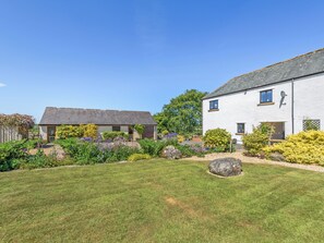 A two-story house with a well-maintained garden, a visible satellite dish, and a paved driveway. - New Park Farm - Church Cottage (near Keswick)
