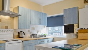 A modern kitchen with light blue cabinets, a stainless steel range hood, a built-in oven, a microwave, and a bread box on the counter. - 2 bedroom accommodation in Keswick (Keswick)