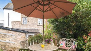 A round table with chairs and an umbrella in a garden setting.