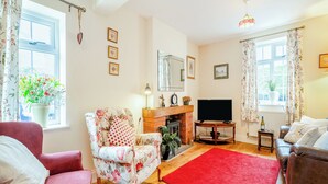 A living room with a fireplace, a television, and floral-patterned furniture.