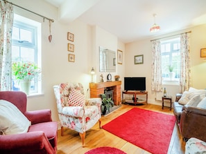 A living room with a fireplace, a television, and floral-patterned furniture.