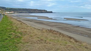 A coastal road with a beach and cliffs in the background.