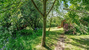A lush garden with a wooden structure, a clear path, and dense foliage.