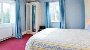 Ein Schlafzimmer mit einem Bett, einem Kleiderschrank und einem Fenster mit Vorhängen.
