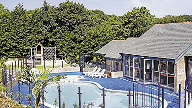 A pool area with a blue deck, lounge chairs, and a covered seating area. - 2 bedroom accommodation in Carnon Downs, near Truro (Carnon Downs, near Truro)