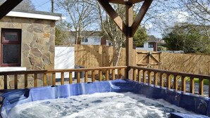 Un jacuzzi con cubierta de madera y paredes de piedra.