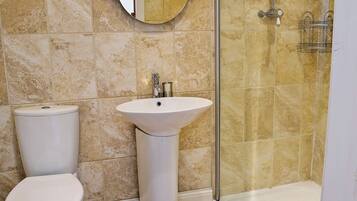 Une salle de bain avec des toilettes, un lavabo et une douche.