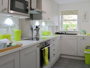 Cozinha moderna com micro-ondas, forno embutido e janela com vista para o verde.