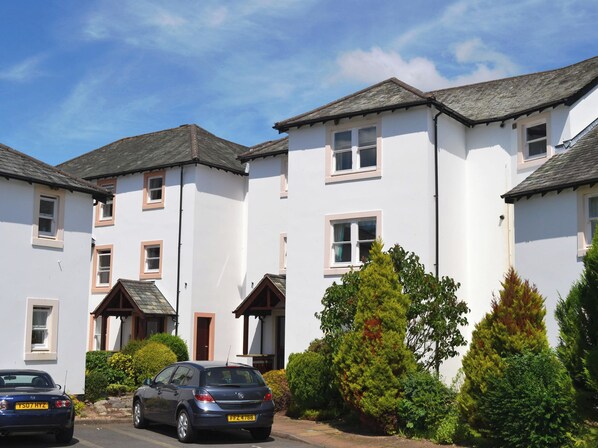 A row of white two-story houses with multiple windows and a garage. - A ground floor apartment with level access, in Keswick. (Keswick)