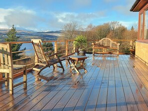 Um deck de madeira com vista para montanhas e um lago.