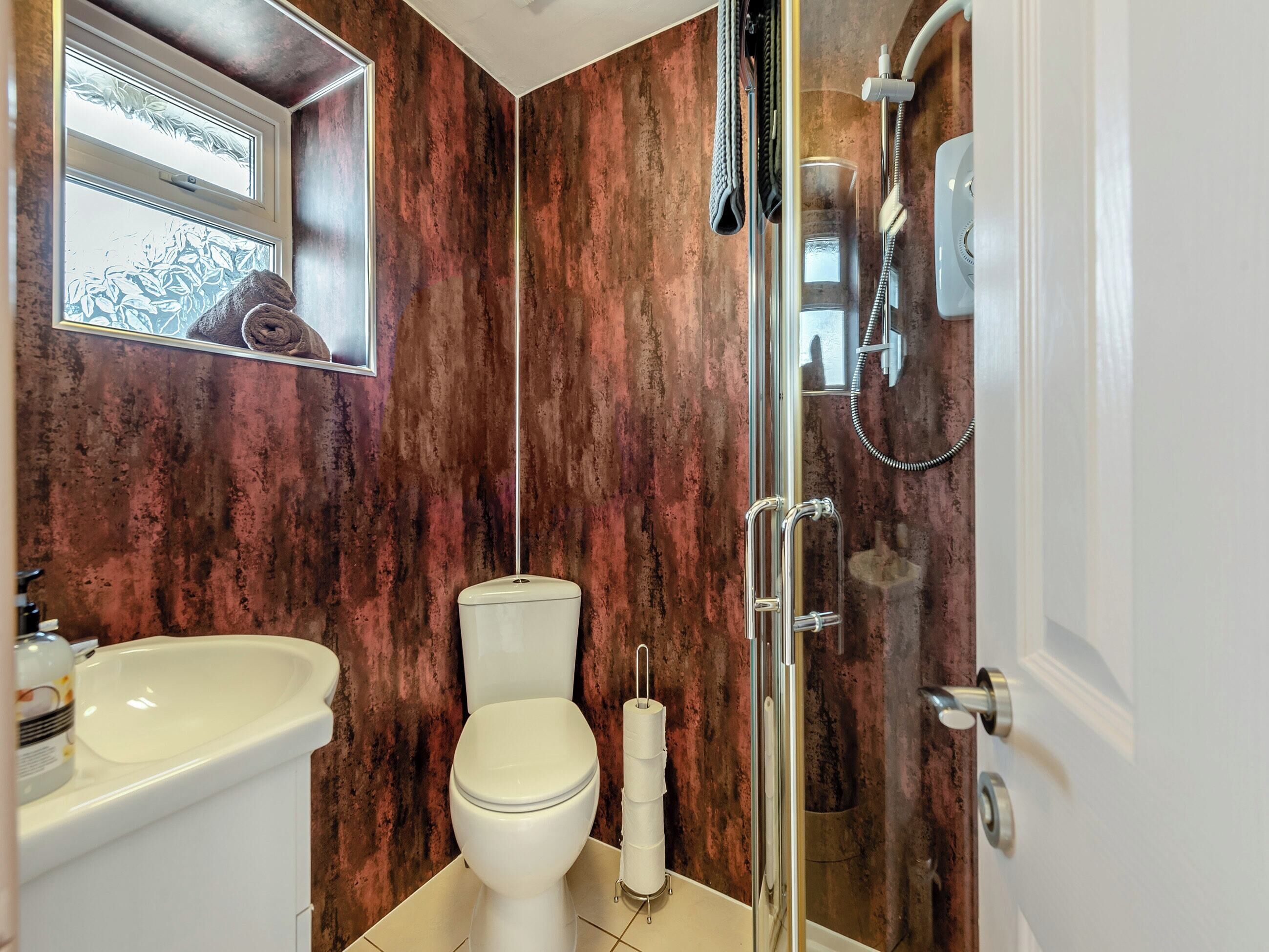 A bathroom with a white toilet, a white sink, and a glass shower enclosure.