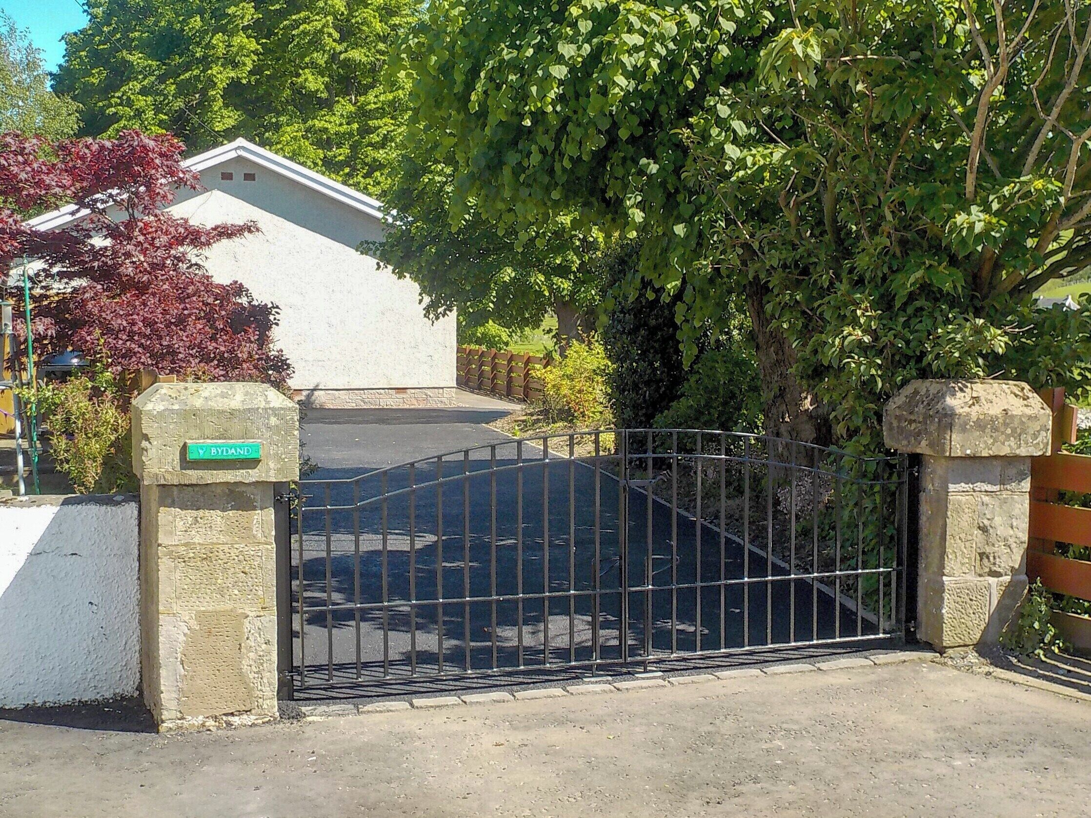 Una entrada cerrada con un pilar de piedra y un letrero que dice 'BYDAND'.