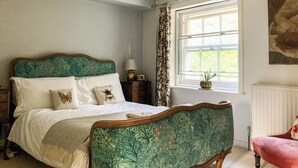 Une chambre à coucher avec un lit, une fenêtre avec des rideaux, un radiateur et un tableau accroché au mur.
