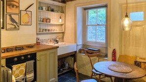 Une cuisine équipée d’une cuisinière, d’un évier et de meubles en bois. Une fenêtre offre une vue sur la verdure environnante.