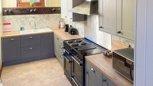 A modern kitchen with grey cabinets, a stainless steel range hood, a built-in oven, and a microwave. - 1 bedroom accommodation in Cantley, near Acle (Cantley, near Acle)