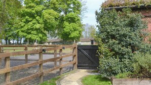 A pathway leading to a fenced area with a wooden gate and a brick wall. - 1 bedroom accommodation in Cantley, near Acle (Cantley, near Acle)