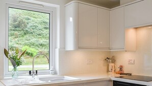 Eine moderne Küche mit weißen Schränken, einer Edelstahl-Spüle und einem schwarzen Backofen.
