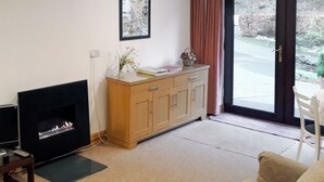A living room with a fireplace, wooden cabinet, and a sofa. - 1 bedroom accommodation in Thornthwaite, near Keswick (Thornthwaite, near Keswick)