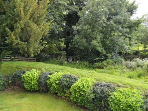 Un jardin luxuriant, agrémenté de divers arbustes et arbres, une clôture en bois et une pelouse bien entretenue.