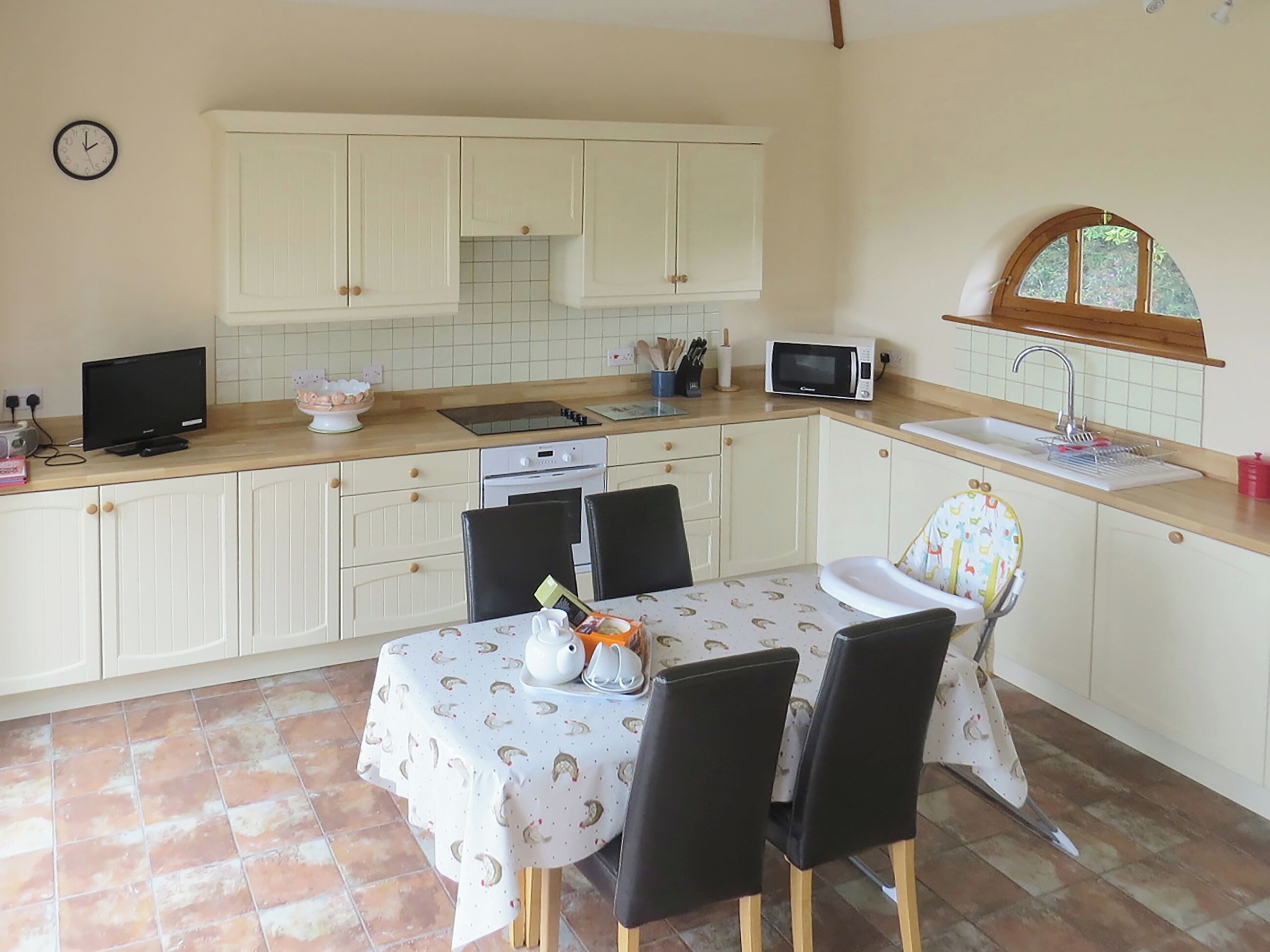 A compact kitchen with white cabinets, a microwave, a sink, and a dining table with chairs.