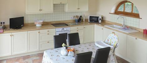 A compact kitchen with white cabinets, a microwave, a sink, and a dining table with chairs.