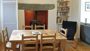 A dining area with a wooden table and chairs, a bookshelf, and a fireplace. - 2 bedroom accommodation in Ambleside (Ambleside)